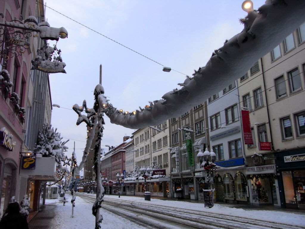 Fußgängerzone in Würzburg mit Weihnachtsdekoration und Schnee.